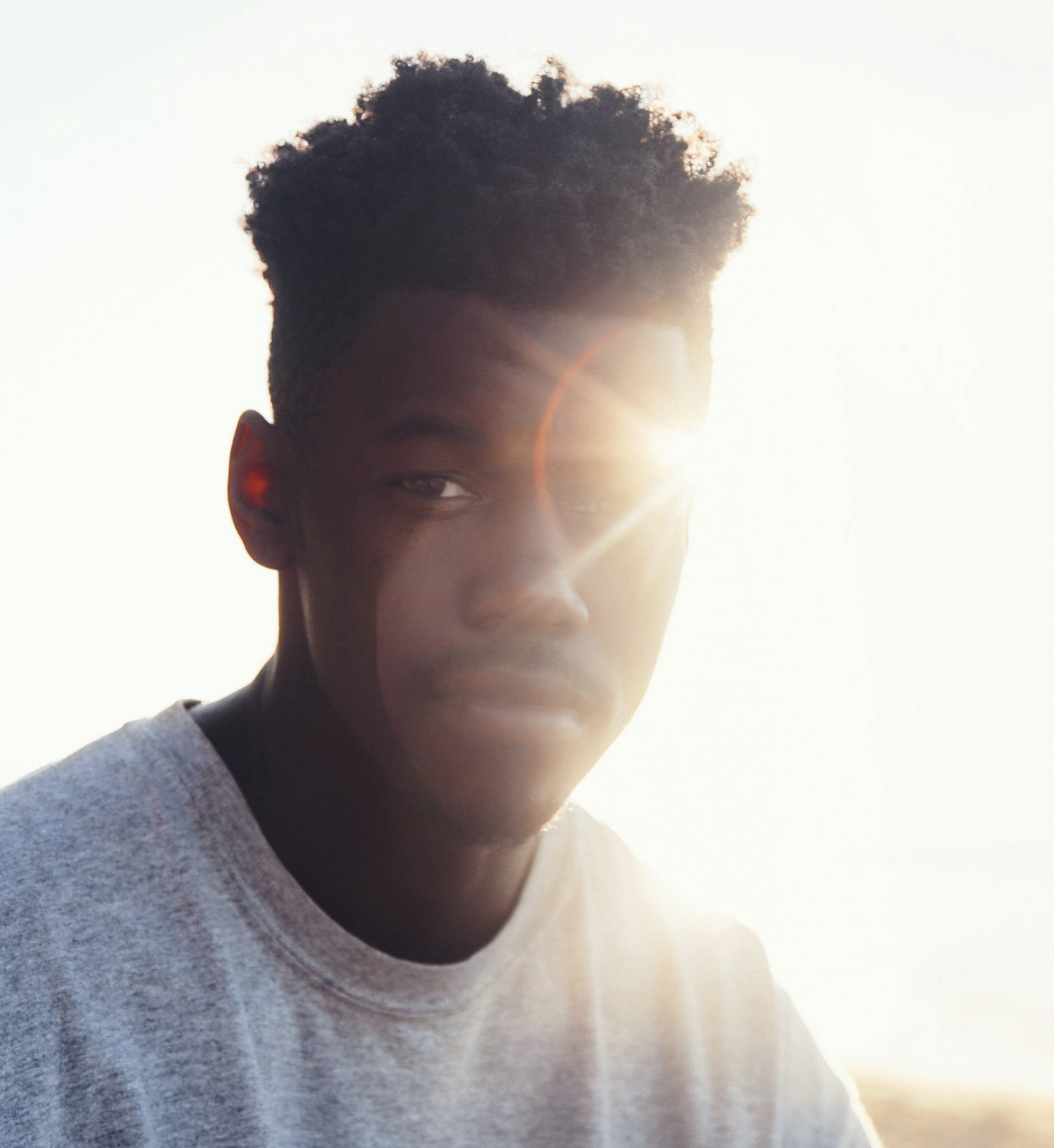 a man in a white t - shirt is staring at the camera