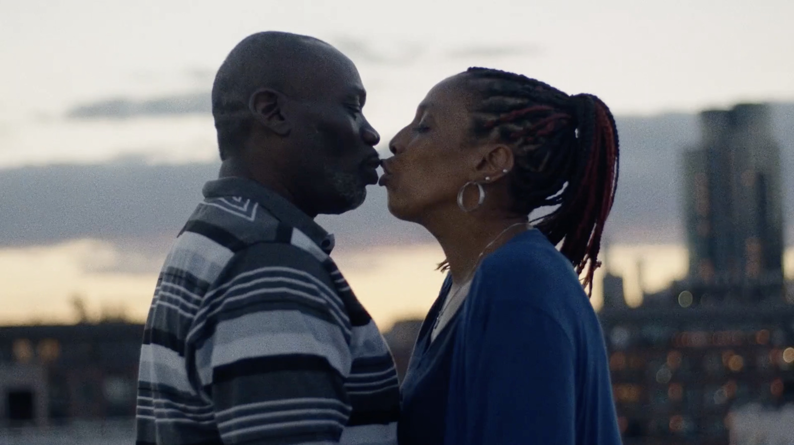 a man and a woman kissing in front of a city skyline