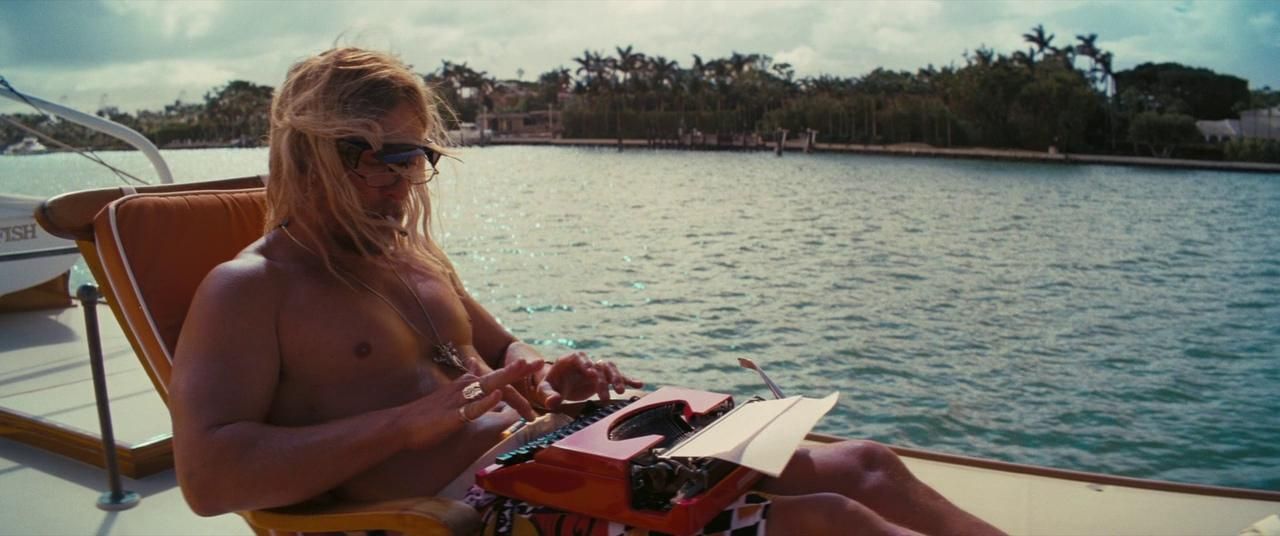 a shirtless man sitting in a chair on a boat