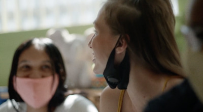 a woman talking on a cell phone while another woman holds a pink object in her