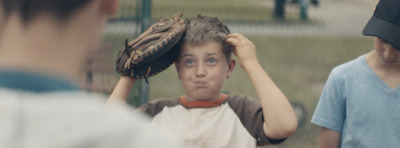 a young boy holding a catchers mitt on top of his head