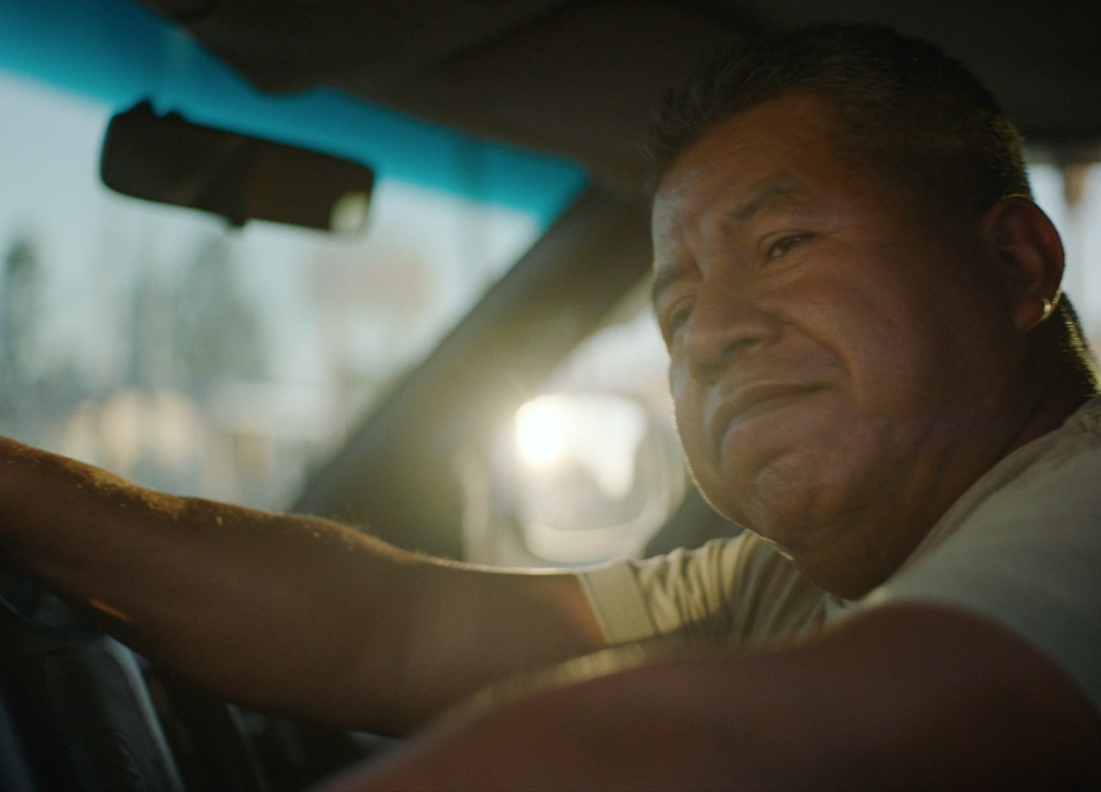 a man driving a car with his hand on the steering wheel