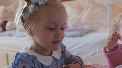 two little girls sitting on a bed playing with toys