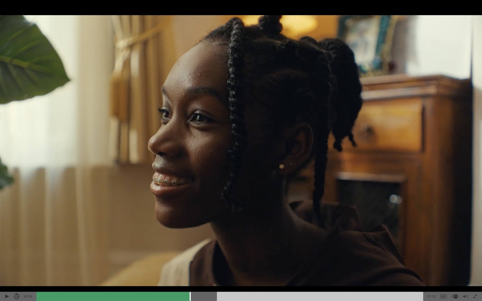 a woman with braids smiling in a living room