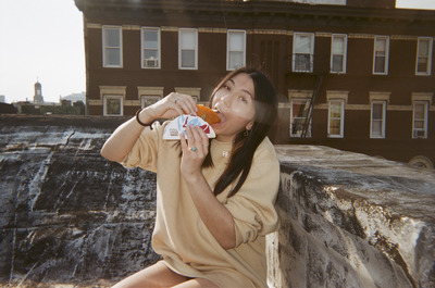 a woman sitting on a ledge eating a donut