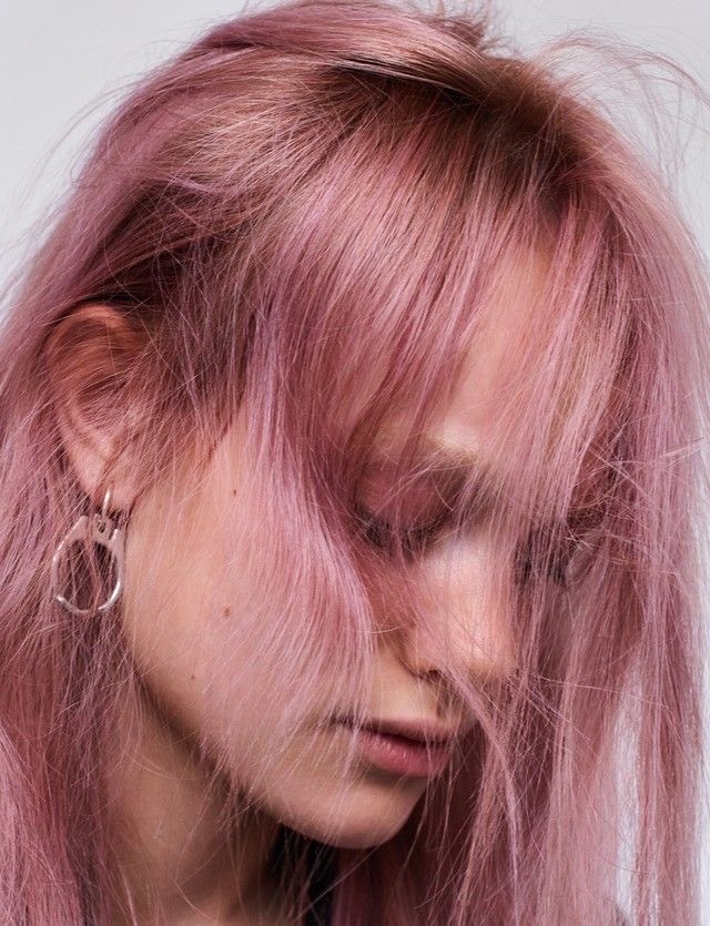 a woman with pink hair and hoop earrings