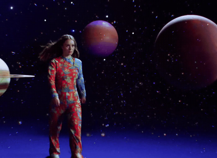 a woman in a space suit standing in front of planets