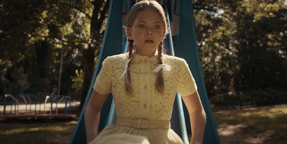 a young girl standing in front of a swing set