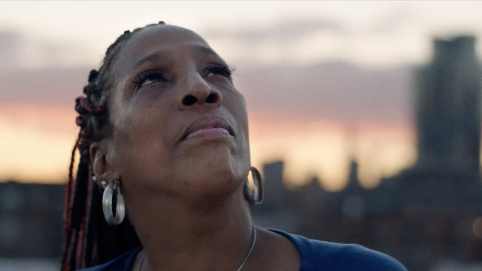 a woman looking up at the sky with a city in the background