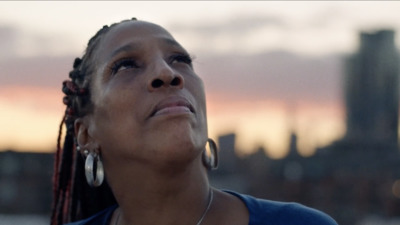 a woman looking up at the sky with a city in the background