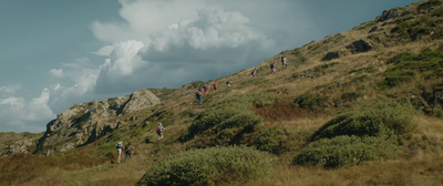 a group of people hiking up a grassy hill