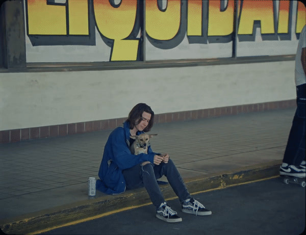 a man sitting on the side of a road with a dog