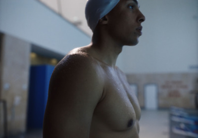 a shirtless man with a swimming cap on