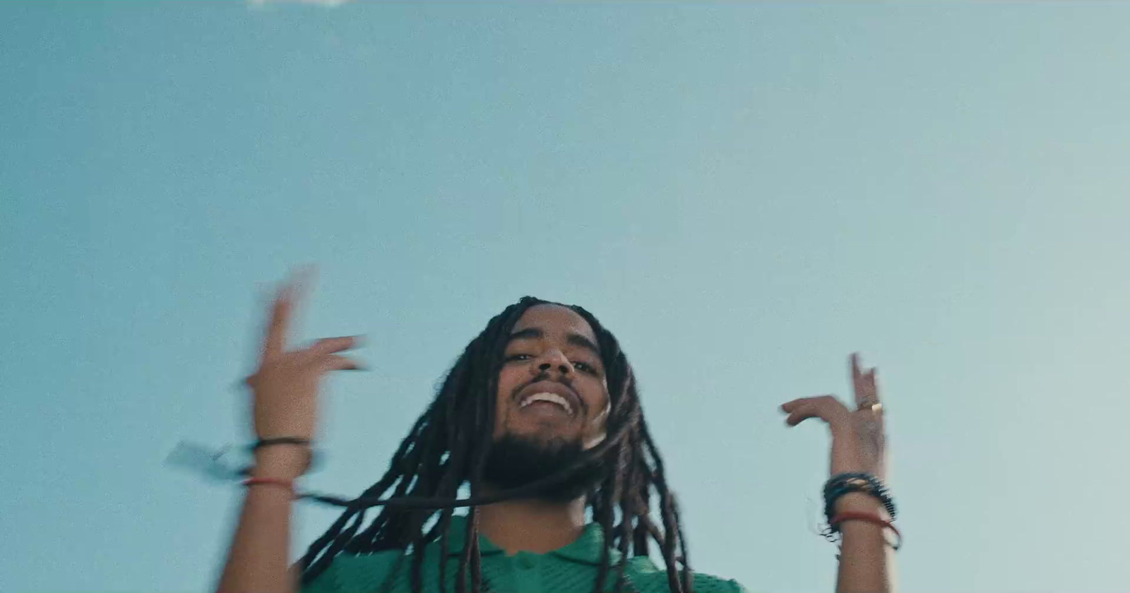 a man with dreadlocks standing in front of a blue sky