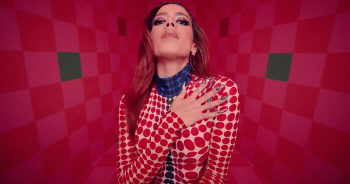 a woman in a red and white shirt with her hands on her chest