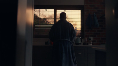 a man in a robe standing in front of a window