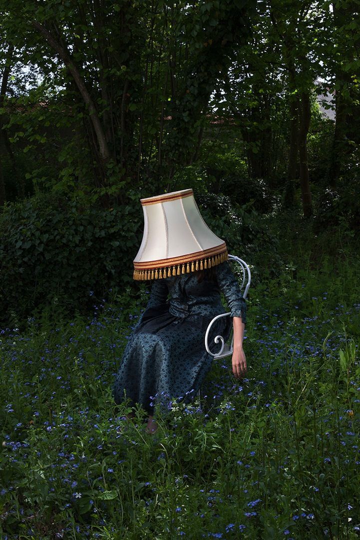 a woman sitting in a field with a lamp on her head