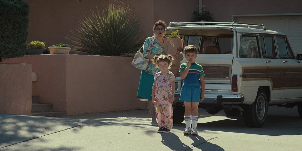 a woman and two children are standing in front of a car