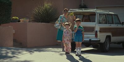 a woman and two children are standing in front of a car