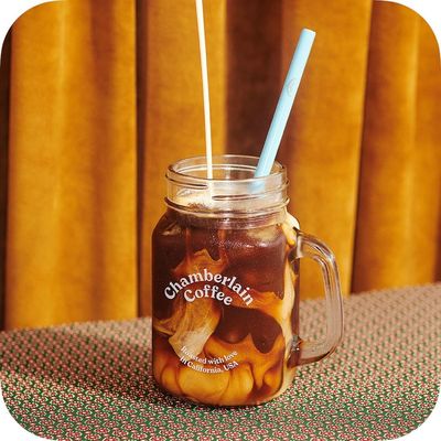 a mason jar filled with a drink and two straws