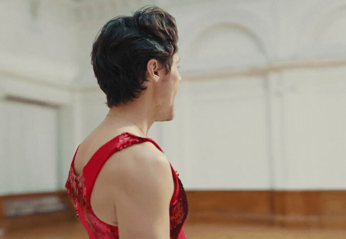 a man in a red dress standing in a room