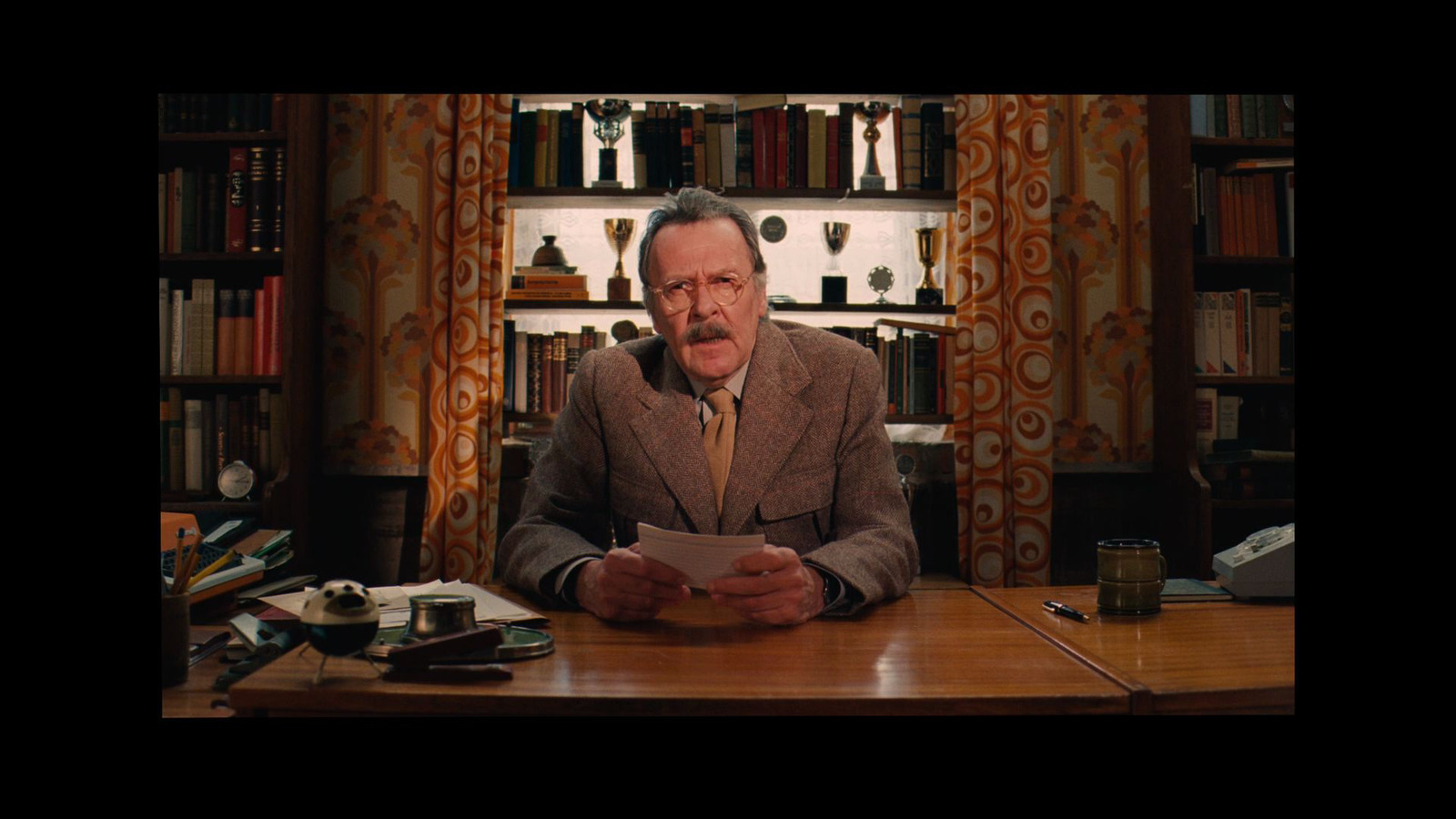 a man sitting at a desk in front of a book shelf