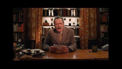 a man sitting at a desk in front of a book shelf