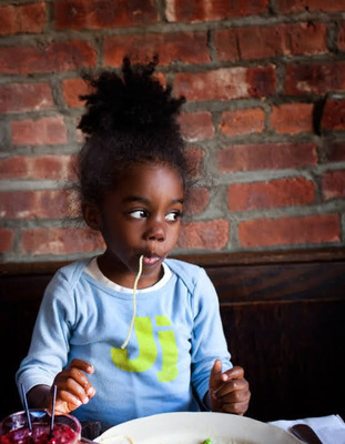 a little girl sitting at a table with a plate of food