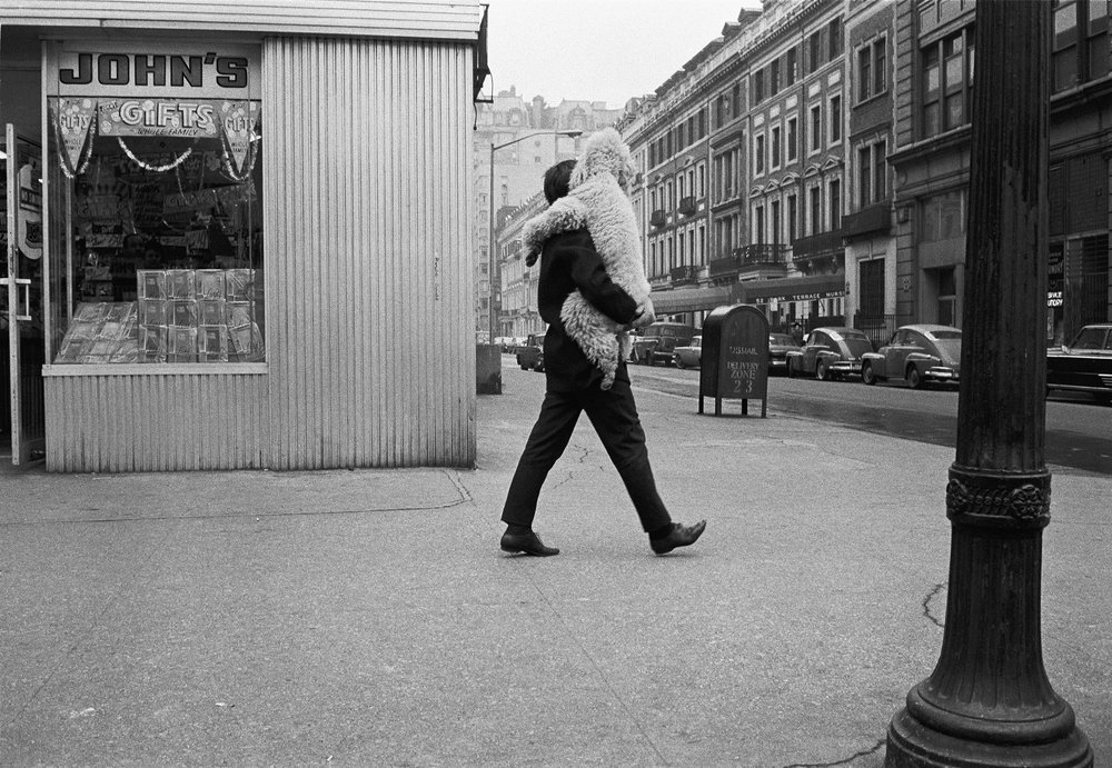 a black and white photo of a man walking down the street