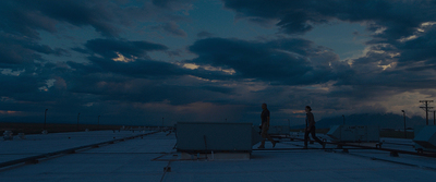 a man standing on top of a roof under a cloudy sky