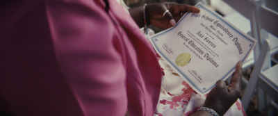 a woman in a pink dress holding a certificate