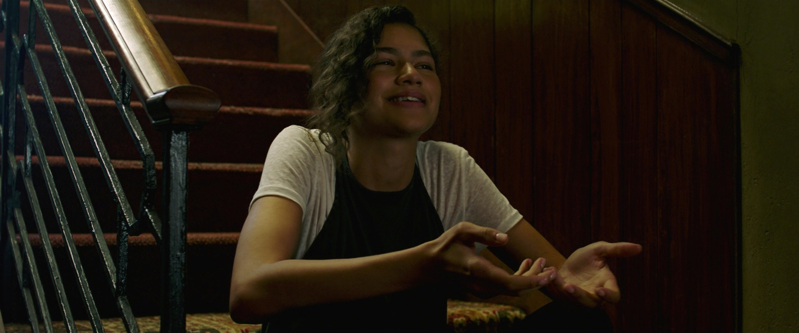 a woman sitting on the ground in front of a stair case