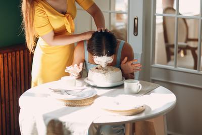 a woman in a yellow dress is putting frosting on a cake