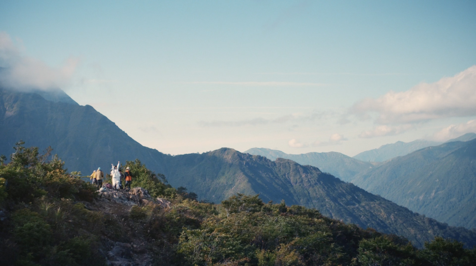 a group of people standing on top of a lush green hillside