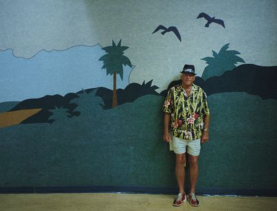 a man standing in front of a painting of palm trees