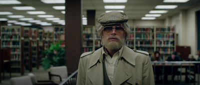 a man wearing a hat and glasses in a library