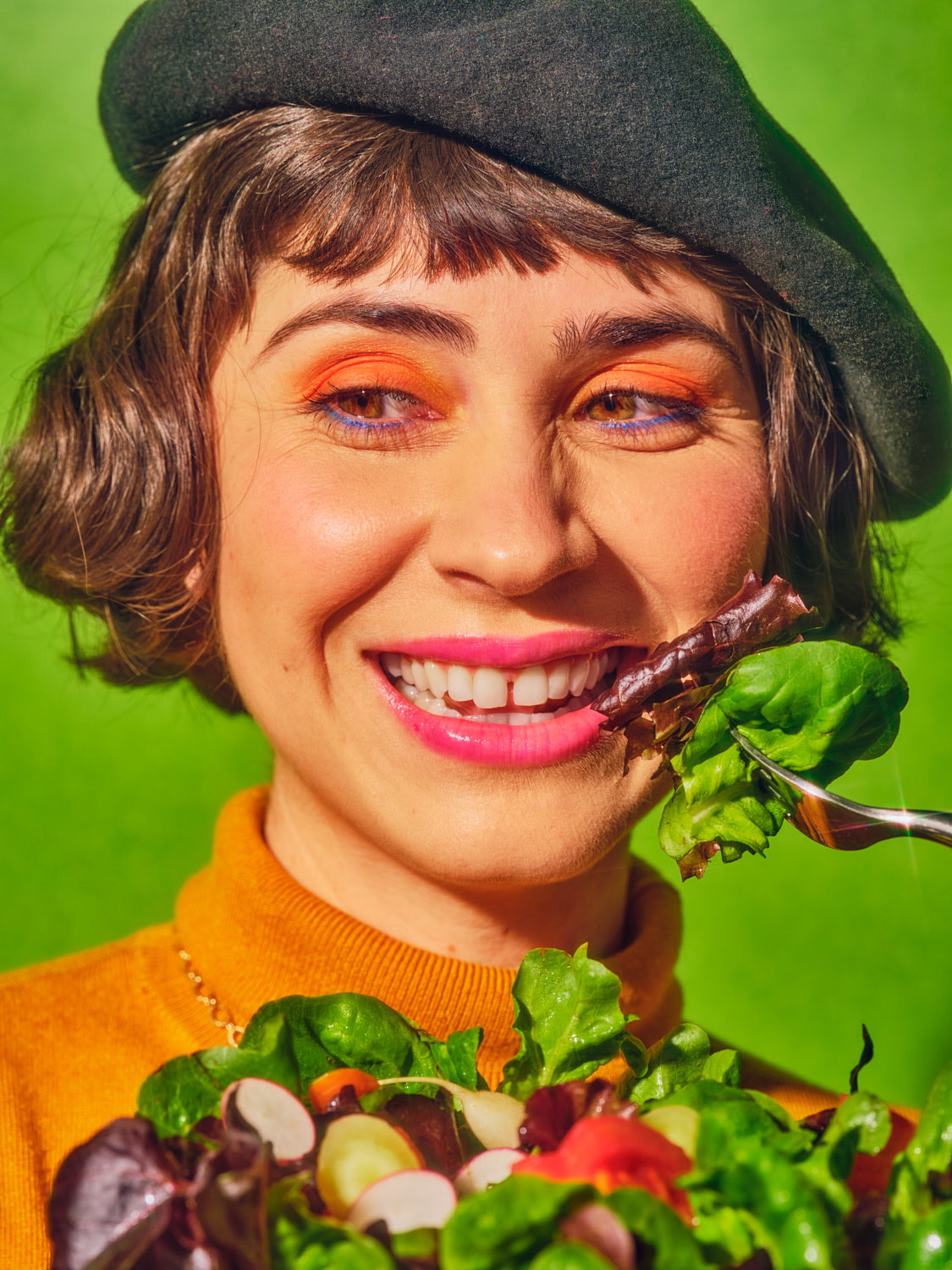 a woman with a green hat is eating a salad