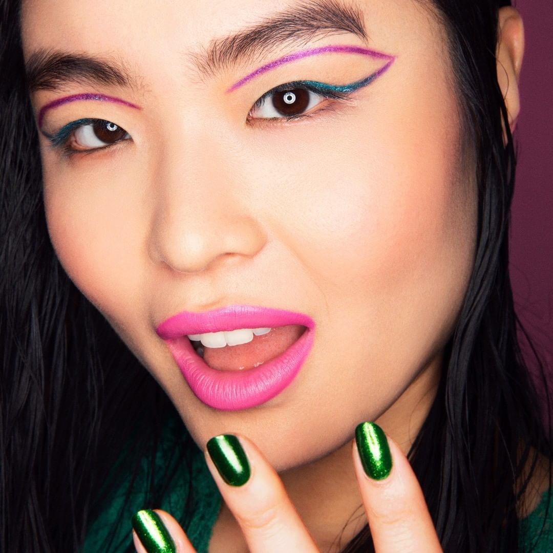 a woman with green and pink nail polish on her nails