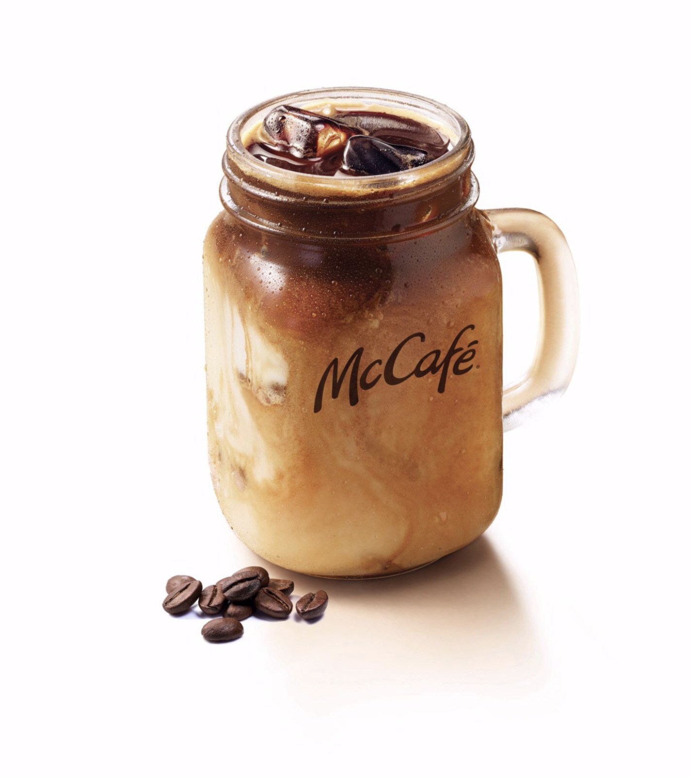 a glass jar filled with coffee beans next to a pile of coffee beans