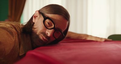 a man with glasses laying on a bed