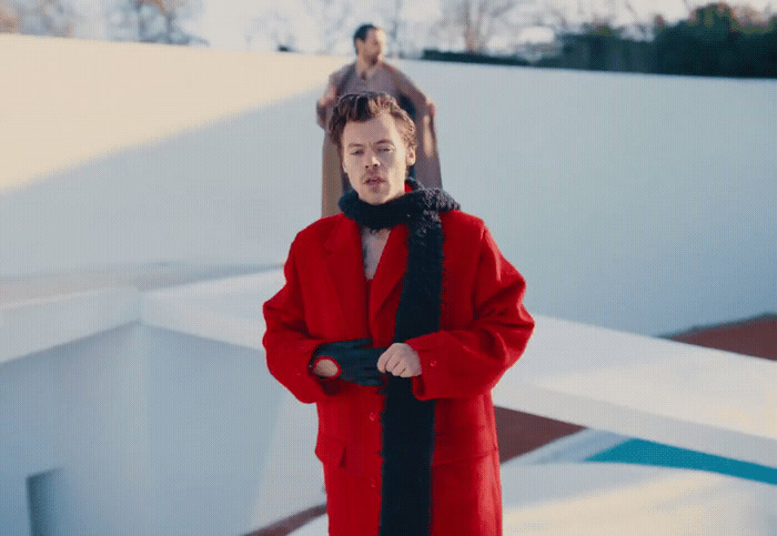 a woman in a red coat standing in front of a statue