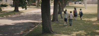 a group of people walking down a sidewalk next to trees