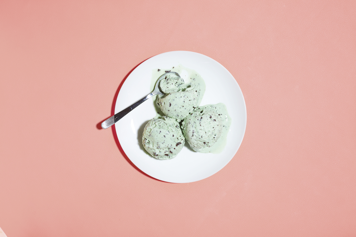 a white plate topped with green cookies on top of a pink table