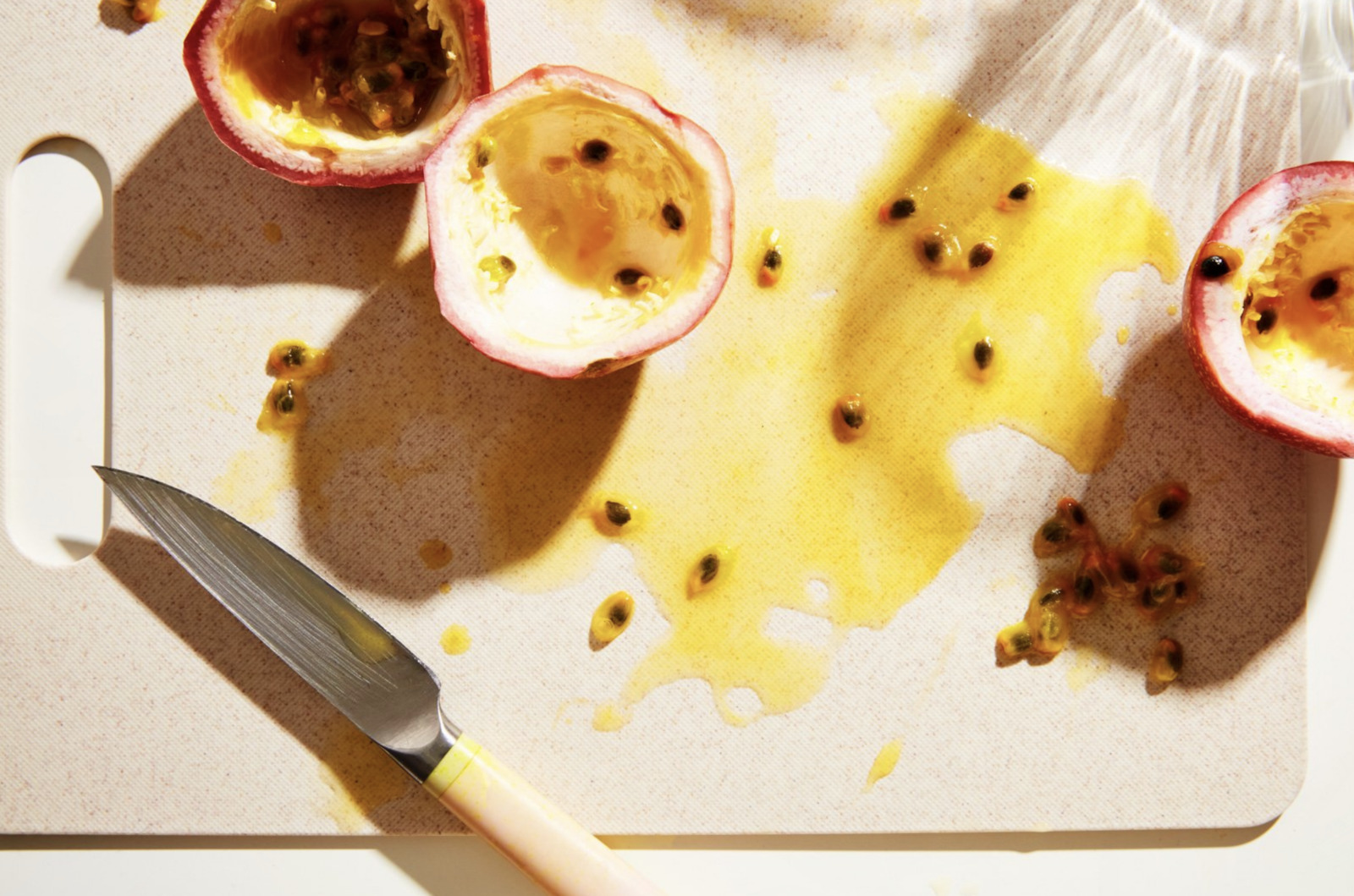 a knife on a cutting board next to a half - eaten pomegranate