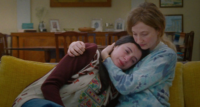 a woman hugging another woman on the couch