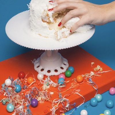 a person grabbing a piece of cake from a plate