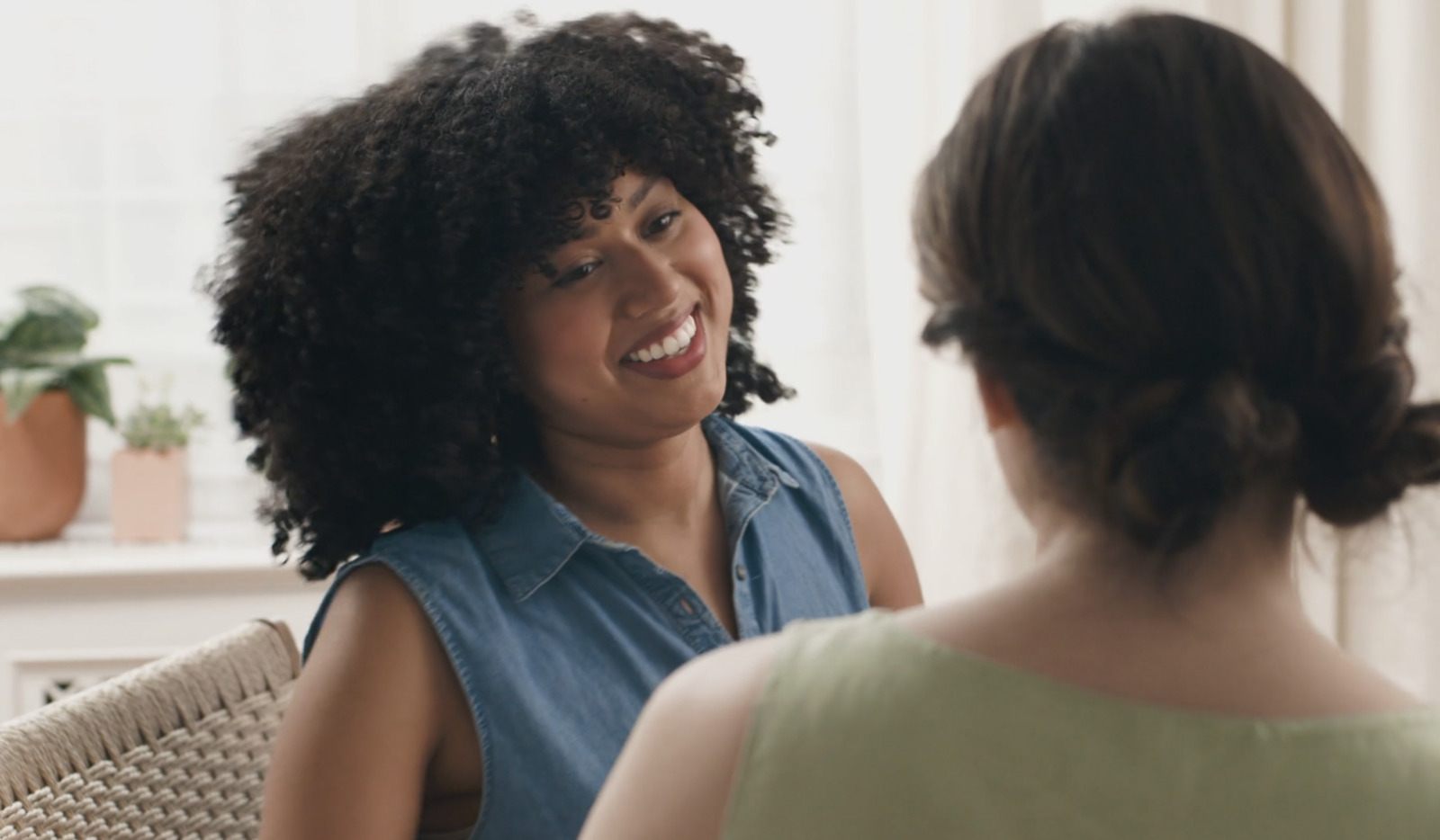 a woman sitting in a chair talking to another woman