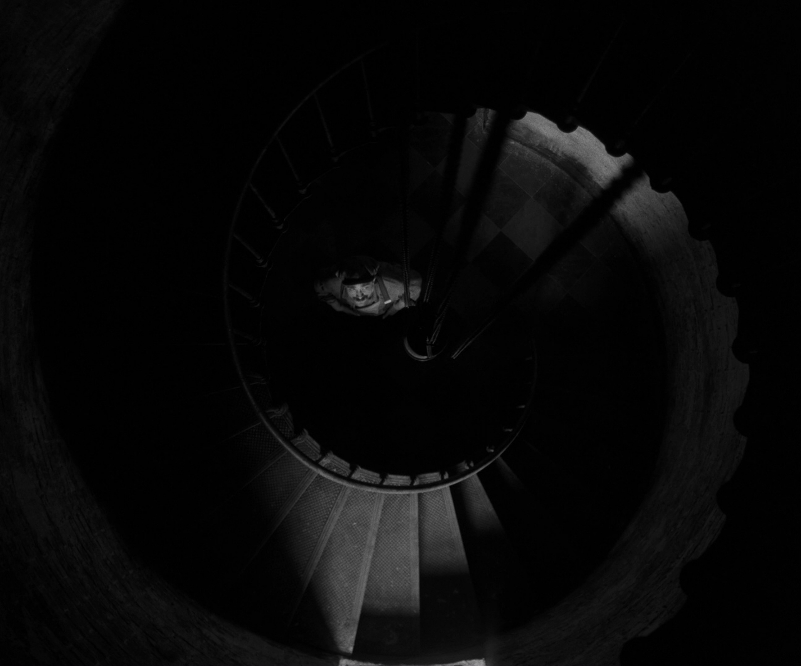 a spiral staircase in a dark room with a person walking up it