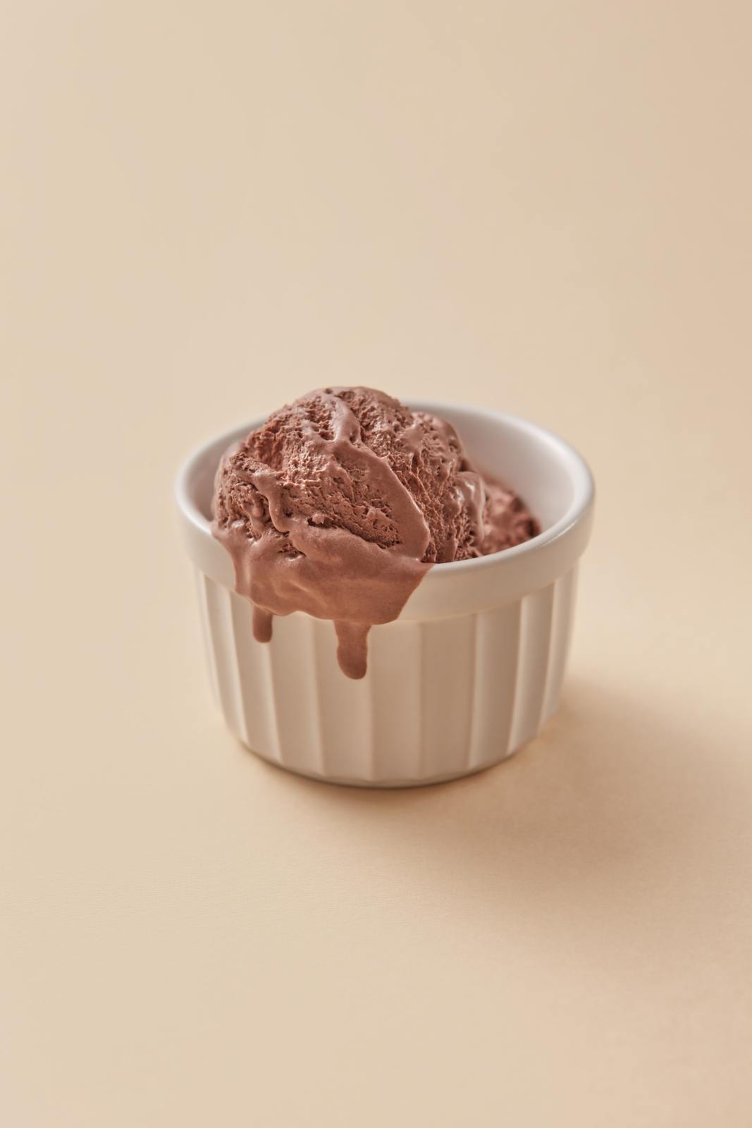 a bowl of chocolate ice cream on a beige background