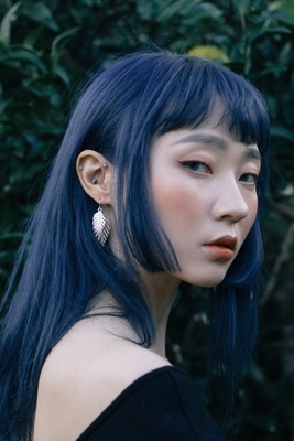 a woman with blue hair wearing a pair of earrings